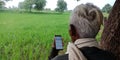 An indian village farmer looking Sbi bank site on mobile phone screen at agriculture field Royalty Free Stock Photo