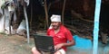 An indian village farmer man working on laptop computer system while seating at home courtyard Royalty Free Stock Photo