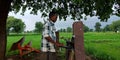 An indian village farmer operating laptop around agriculture field at bicycle base