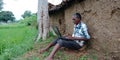 An indian village farmer operating laptop computer system seating at agriculture field Royalty Free Stock Photo