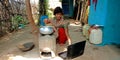 An indian village girl operating laptop while cooking at courtyard