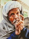 Indian village old man smoking Ganja Marihuana with chillum/hukkah in Rajasthan's traditional dress turban on head in winter