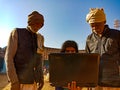 indian village people learning about laptop from school girl at open background in india January 2020