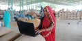 An indian village woman operating laptop computer system at agriculture produce market