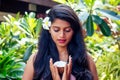 Indian woman applying coconut oil dark brunette long hair in a hand on green summer park nature tropical Royalty Free Stock Photo