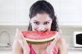 Indian woman biting watermelon in the kitchen Royalty Free Stock Photo