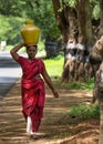 Indian woman carries pot of water on her head.