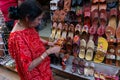 Indian woman checking pairs of Rajasthani womens` shoes at display for sale.