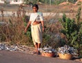 Indian woman collecting fish which was dried right on the ground along the road