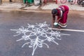 Indian woman drawing Kolam (Rangoli) - form of painting drawn by using rice powder in front of the house
