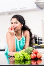 Indian woman eating healthy apple in her kitchen Royalty Free Stock Photo