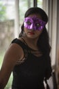 Indian woman in erotic mood standing in front of a glass wall wearing pink eye mask. Royalty Free Stock Photo