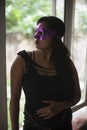 Indian woman in erotic mood standing in front of a glass wall wearing pink eye mask.