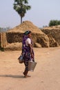 Indian woman farmer carrying metal water bucket