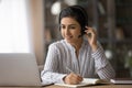 Indian woman in headphones work online on laptop