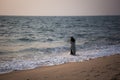 An Indian woman with long hair and a long dress entered the sea at sunset.