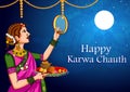 Indian woman looking moon through sieve during Karwa Chauth celebration