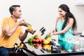 Indian woman and man in kitchen with red wine