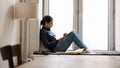 Indian woman rest on windowsill spend leisure use digital tablet Royalty Free Stock Photo