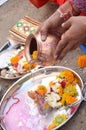 Indian woman`s hands holding a bowl over a plate with flowers during a traditional ritual