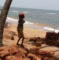 The Indian woman in a sari stones for building on the head on a beach. India Goa