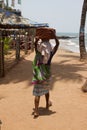 The Indian woman in a sari stones for building on the head on a beach. India Goa