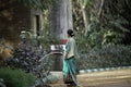 Indian woman in a sari watering flowers at Karanji Lake in Mysore, India