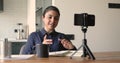 Indian ethnicity woman sitting at desk record videovlog on smartphone