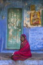 An Indian woman sitting outside the house, in the blue city, the old town of Jodhpur