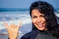 Indian woman with snow-white smile girl in wetsuit showing gesture mahalo shaka hand sign signal saying hello on Royalty Free Stock Photo