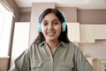 Indian woman student teacher wearing headphones looking at web cam.