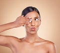 Indian woman, studio and beauty with hand on eye for funny face, pouting and cosmetics by background. Gen z model girl Royalty Free Stock Photo