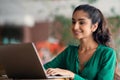 Indian woman studying online at cafe, using laptop, empty space Royalty Free Stock Photo