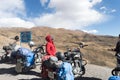 Indian woman traveler trekker and Biker standing beside her motorcycle, hiking high Himalayan Mountain region outing and exploring