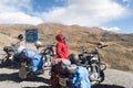 Indian woman traveler trekker and Biker standing beside her motorcycle, hiking high Himalayan Mountain region outing and exploring