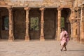 Indian woman walking through courtyard of Quwwat-Ul-Islam mosque