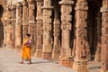 Indian woman walking through courtyard of Quwwat-Ul-Islam mosque