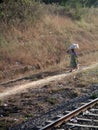 Indian woman walking next to railroad balancing bag on her head