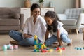 Indian woman and daughter play wooden blocks seated on floor