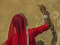 An Indian women painting a mural in the city of Jaisalmer with traditional clothes/sari/saree