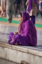 Indian women in purple sari sitting near the lake at Golden Temple. Amritsar. India Royalty Free Stock Photo