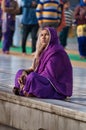 Indian women in purple sari sitting near the lake at Golden Temple. Amritsar. India Royalty Free Stock Photo