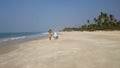 Indian women walk with wicker baskets on their heads on sandy beaches. Kolva, India.