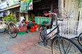 A indian work in front of shop with old bicycle parking in front.