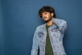 Indian young bearded man over blue studio background confuse and wonder about question. Uncertain with doubt, thinking with hand