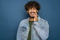 Indian young bearded man over blue studio background confuse and wonder about question. Uncertain with doubt, thinking with hand