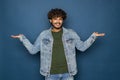 Indian young bearded man over blue studio background confuse and wonder about question. Uncertain with doubt, thinking with hand