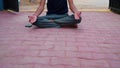 A boy is meditating at home in India. Indian young boy in a black traditional shirt sitting in a lotus position