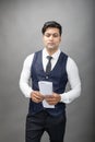 Indian young business man giving presentation on a topic holding folder in hand in formal wear wearing white shirt, black tie, Royalty Free Stock Photo