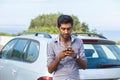 Indian young business man looking communicating on mobile phone  next to his car outdoors background Royalty Free Stock Photo